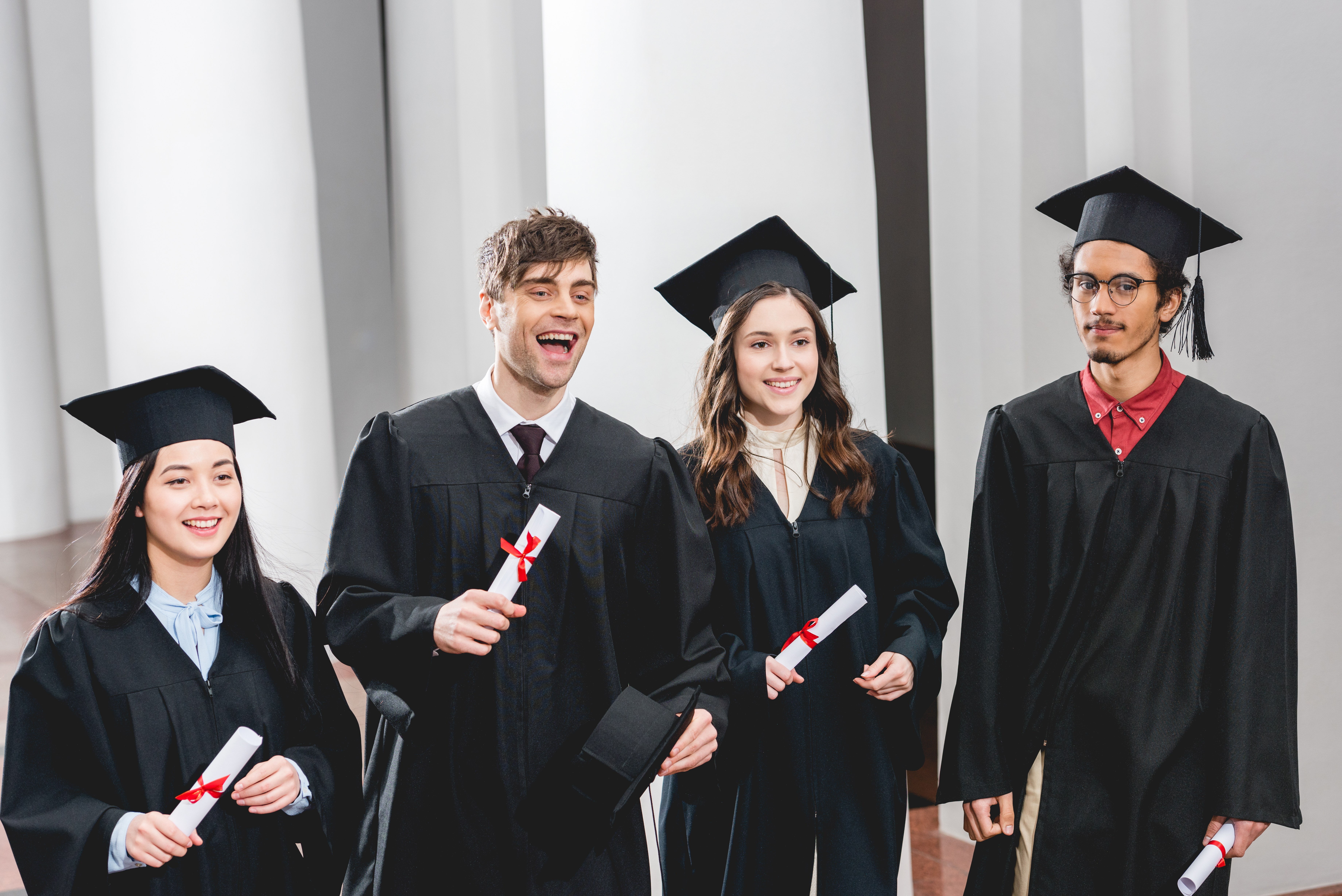 smiling group on students in graduation gowns holding diplomas